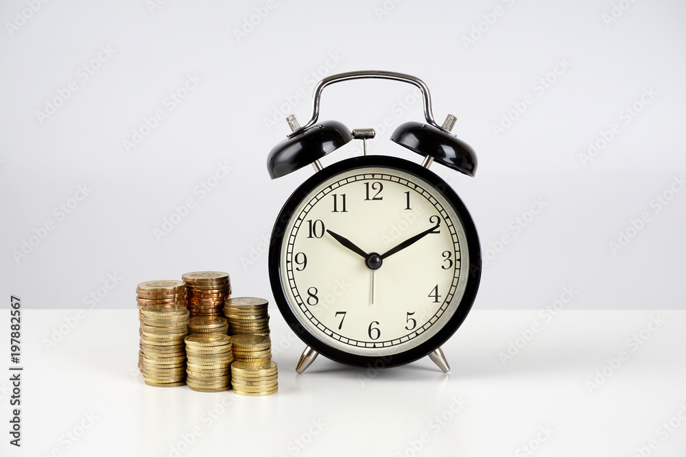Alarm clock and coins on a white surface Alarm clock and coins on a white surface