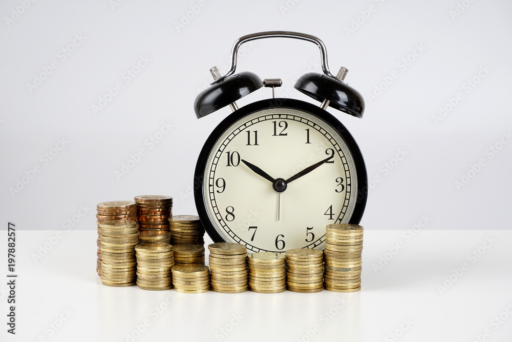 Alarm clock and coins on a white surface