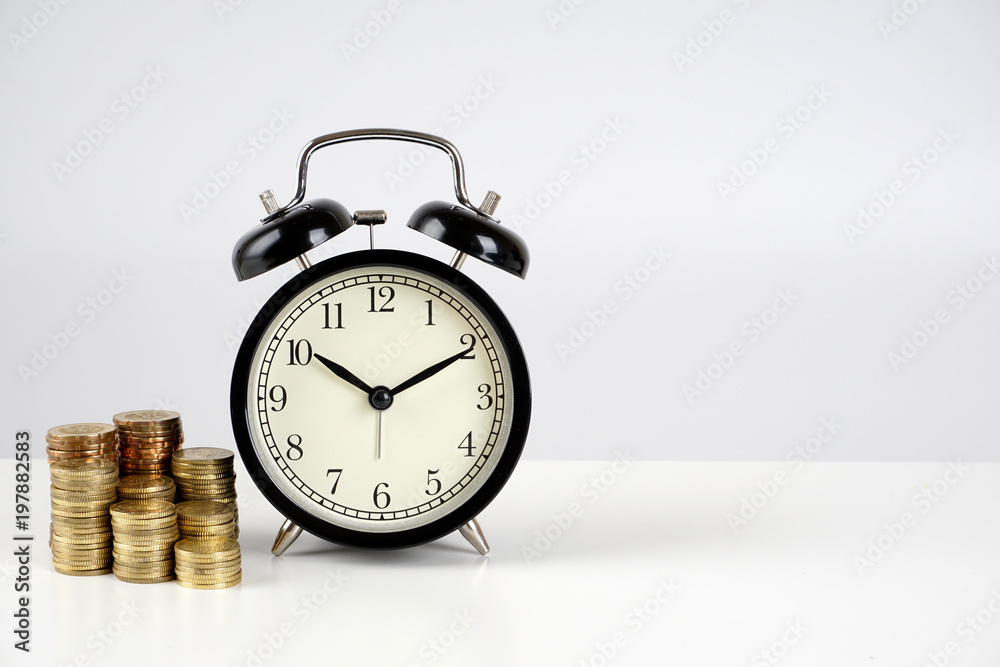 Alarm clock and coins on a white surface Alarm clock and coins on a white surface