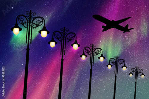 Flying aircraft and vintage lampposts at night. Vector illustration with silhouette of passenger airplane. Northern lights in starry sky.