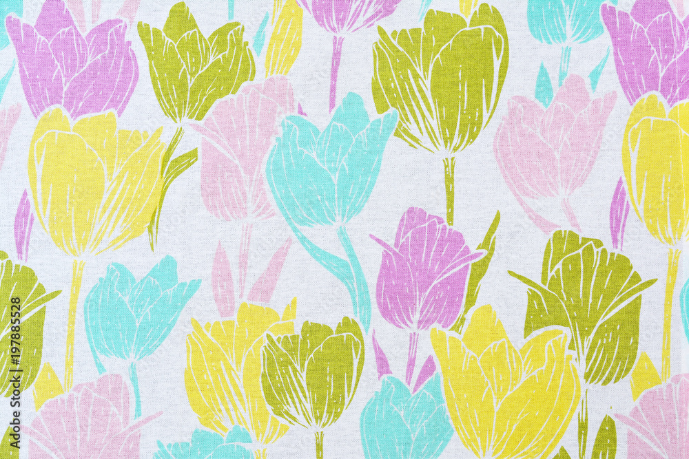 Floral pattern from multi-colored tulips on a white cotton tablecloth.