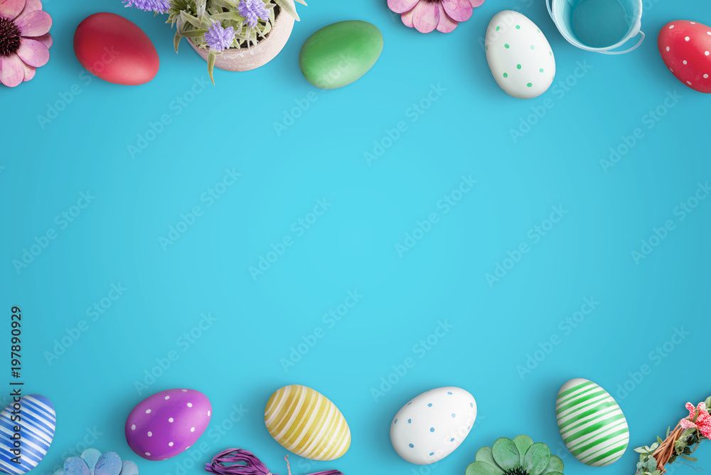 Easter eggs and flowers on blue surface. Flat lay, top view scene with free space for text.