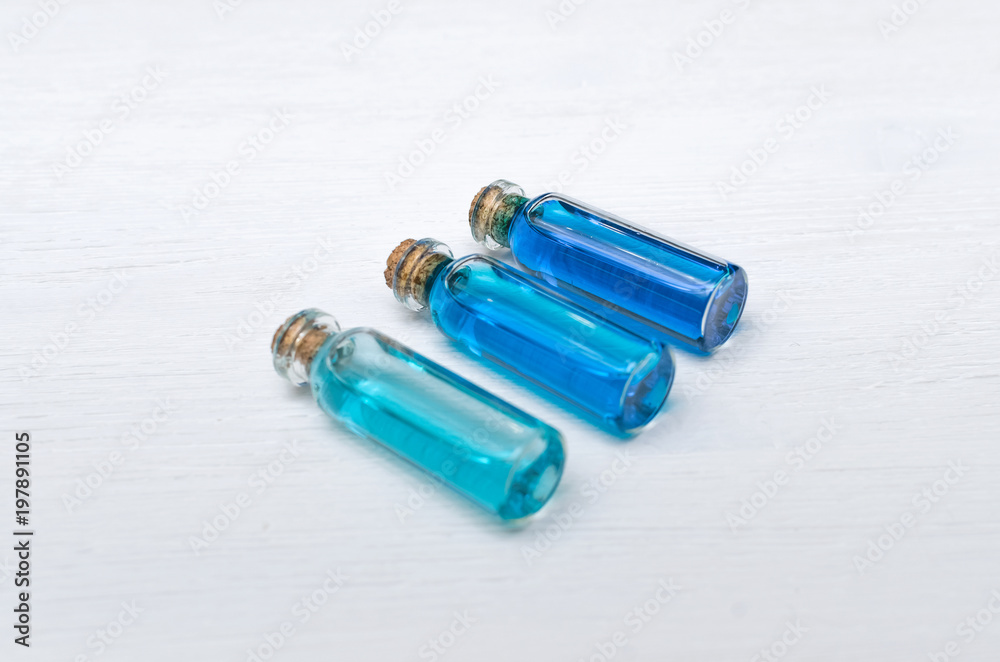 Blue essential oil tincture bottles of different transparency on white wooden background. Alternative medicine. Herbal medicine. Aroma therapy. Blue essential oil tincture bottles of different transparency on white wooden background. Alternative medicine. Herbal medicine. Aroma therapy.