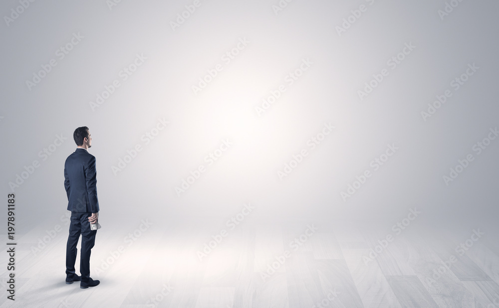 Man standing with his back in an empty room with object in his hand Man standing with his back in an empty room with object in his hand