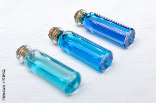 Blue essential oil tincture bottles of different transparency on white wooden background. Alternative medicine. Herbal medicine. Aroma therapy.