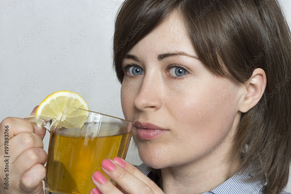 Beautiful girl with blue eyes drinking tea with lemon. Pink manicure. Front view. Beautiful girl with blue eyes drinking tea with lemon. Pink manicure. Front view.