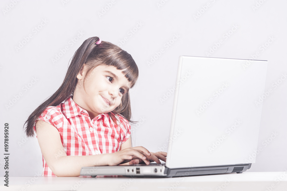 Cute little girl having fun using her laptop. Education, technology and e-learning concept Cute little girl having fun using her laptop. Education, technology and e-learning concept