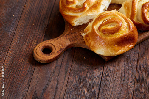 Homemade rose buns on wooden cutting board over rustic vintage background, close-up, shallow depth of field photo