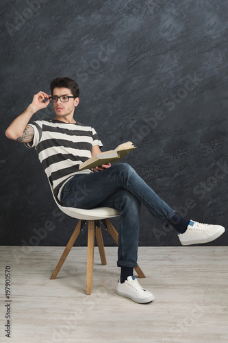 Young thoughtful tattooed man with book