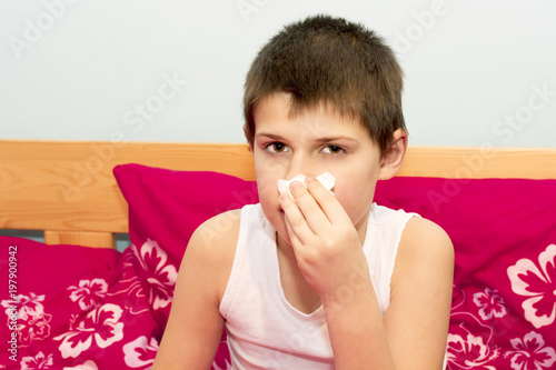 The boy stops bleeding from his nose with a handkerchief. The flu season. Influenza epidemic in the Czech Republic. Nose injury with bleeding.