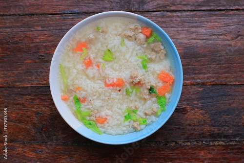 Thai rice soup with pork breakfast food on wooden background 