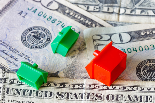 Overturned miniature houses on top of American USD dollar currency symbolising expensive houses and flats