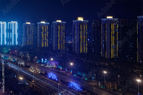 Illuminated modern skyscraper buildings at the motorway by night, Shenyang, China
