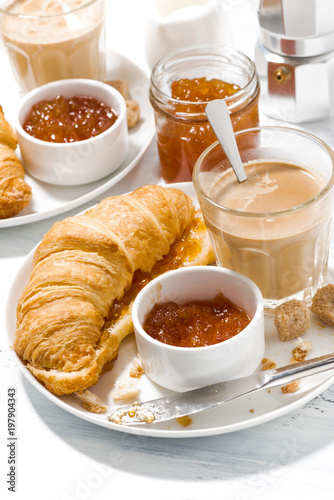 croissants with jam and coffee with milk for breakfast on white table  vertical