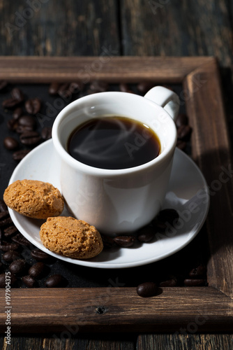 cup of black coffee and cookies on a tray, vertical closeup