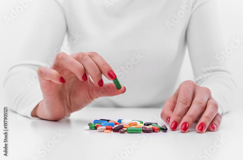 Woman chooses medicine from a handful of different color tablets.