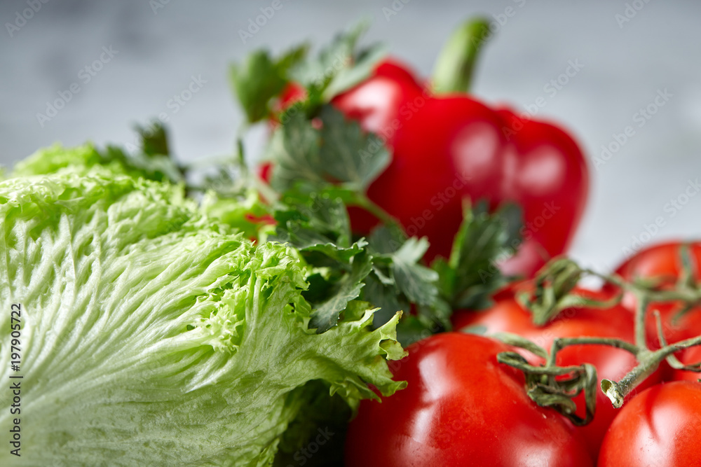 Bunch of fresh tomatoes with green leaves on stony board over white background, top view, close-up, selective focus