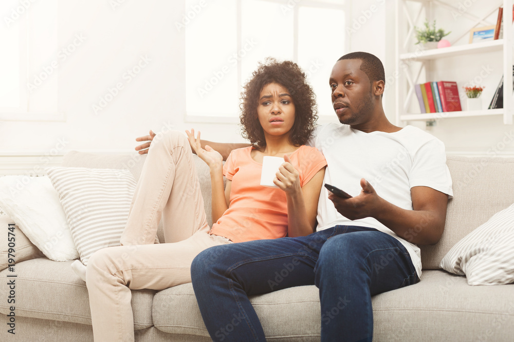 Surprised black couple watching TV at home