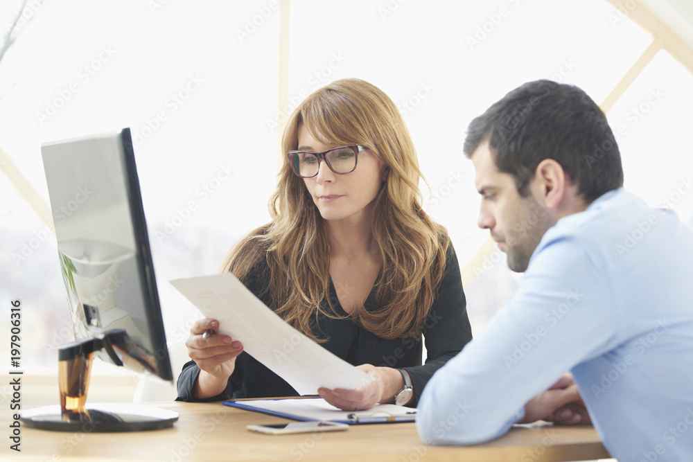 Executive businesswoman giving advice to young professional man. Investment advisor woman sitting in front of laptop with young financial assistant businessman and consulting at the office. Executive businesswoman giving advice to young professional man. Investment advisor woman sitting in front of laptop with young financial assistant businessman and consulting at the office.