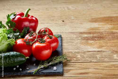 Close-up still life of assorted fresh vegetables and herbs on wooden rustic background, top view, selective focus.