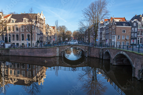 water canals in Amsterdam with a bridge in the middle and traditional architecture