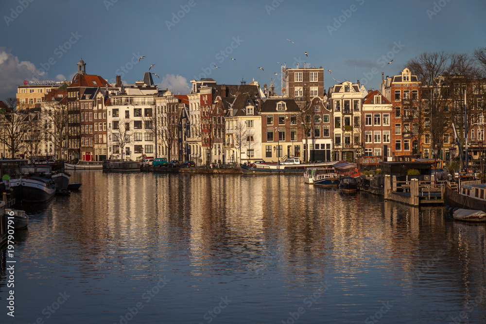 water canals in Amsterdam with  traditional architecture reflecting in the water on a sunny day