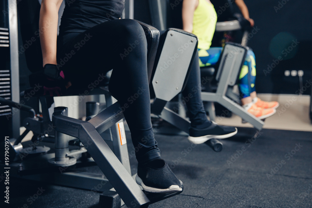 Leg training in hip muscle simulator. Girls train glutes of fitness, pushing legs in block. Leg training in hip muscle simulator. Girls train glutes of fitness, pushing legs in block.