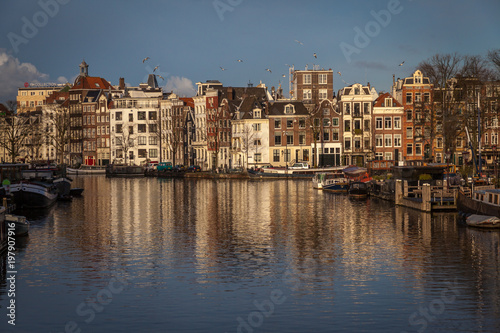 water canals in Amsterdam with traditional architecture reflecting in the water on a sunny day
