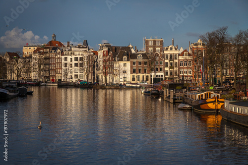 water canals in Amsterdam with traditional architecture reflecting in the water on a sunny day © osnuya