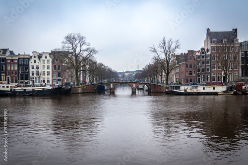 water canals in Amsterdam with a bridge in the middle and buildings on both of bridge's side 