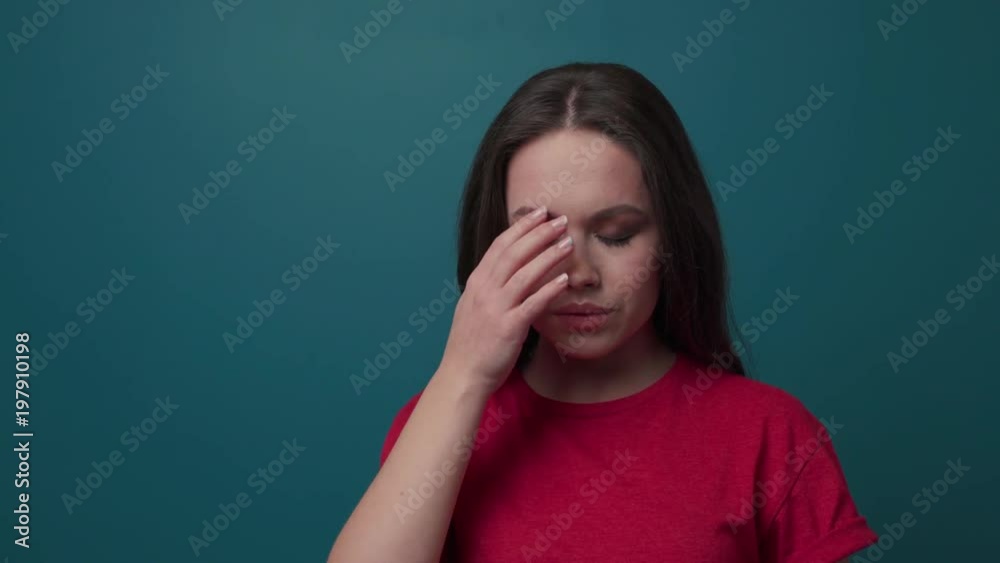 Attractive young woman on a dark green background has a terrible headache, massages her head. Pain, unhealthy, having troubles. Slow motion, close up view, female portrait Attractive young woman on a dark green background has a terrible headache, massages her head. Pain, unhealthy, having troubles. Slow motion, close up view, female portrait