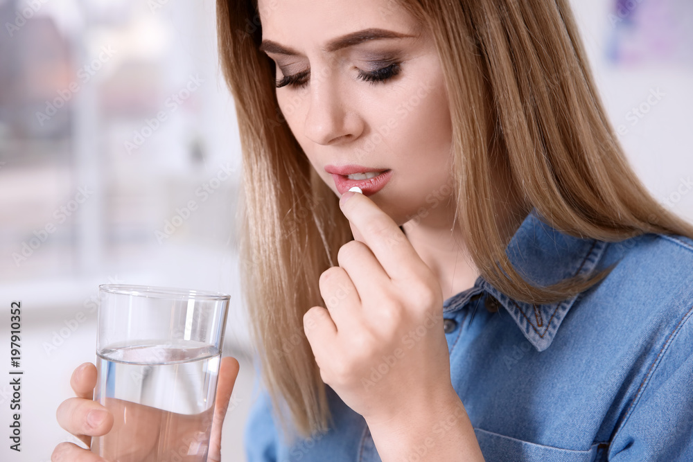 © New Africa - Young woman taking pill indoors © New Africa - Young woman taking pill indoors