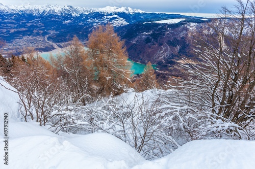 Snow covered forest with lake and mountains background, Col Visentin, Belluno, Veneto, Italy photo