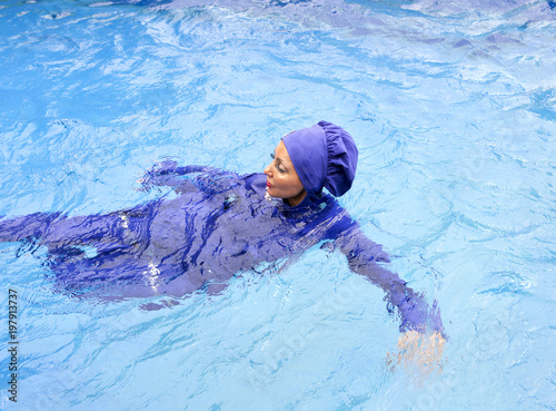 attractive woman in a Muslim swimwear  burkini swims in the pool photo
