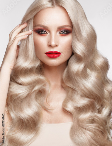 Beautiful blonde in a Hollywood manner with curls  natural makeup and red lips.. Beauty face and hair. Picture taken in the studio
