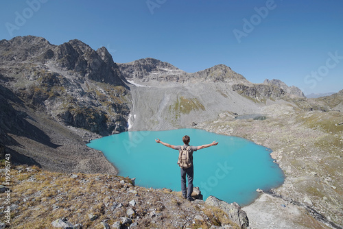 Traveler in rocky mountains staring at the lake.