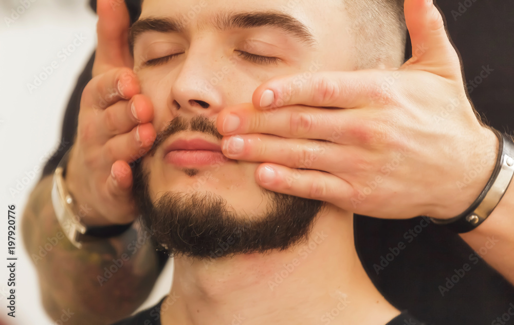Obraz premium A young hairdresser who does a haircut and styling an attractive man in a hair salon