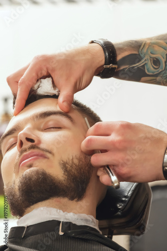 Client during beard shaving in barber shop