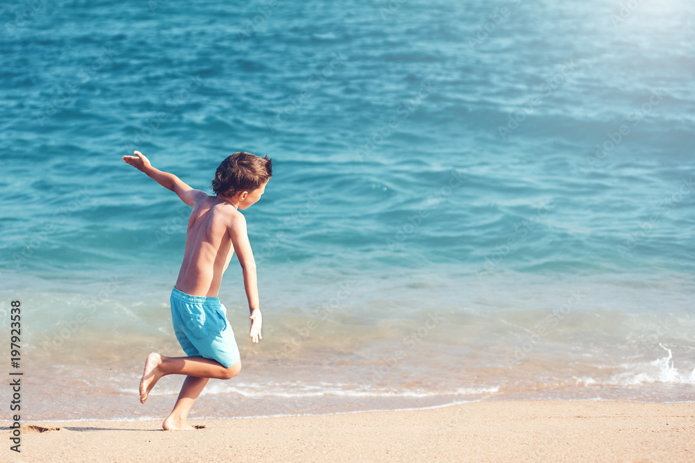Cute european boy is running along the seacost. He is hsving fun and enjoing his holidays. Cute european boy is running along the seacost. He is hsving fun and enjoing his holidays.