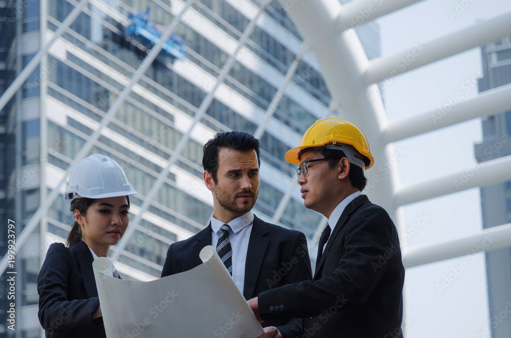group of business or engineer woman and man with safety helmet and blueprint planning at the building and checking their work in modern city, planning start up new project, successful concept group of business or engineer woman and man with safety helmet and blueprint planning at the building and checking their work in modern city, planning start up new project, successful concept