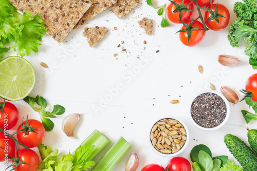 Top view of fresh vegetables anf whole grain breads over white background. Healthy and organic food frame. Flat lay.