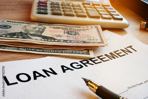 Loan agreement, money and calculator on a desk.