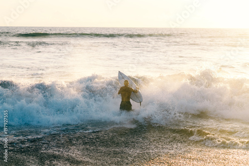 Surfer man entering the ocean