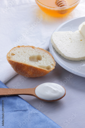 Cheese  honey and sour cream  feta in a white plate  soft cheese on a white background  wooden spoon with sour cream  French breakfast  blue napkin  honey in glassware  blank for designer