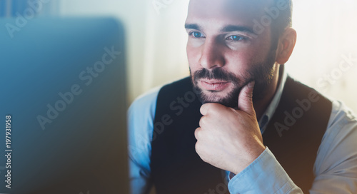 Bearded young businessman working on modern office. Consultant man thinking looking in monitor computer. Manager typing on keyboard in coworking workplace, startup project concept photo