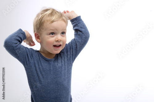 Excited blonde toddler with hands up. Isolated. Studio shot. Copy space