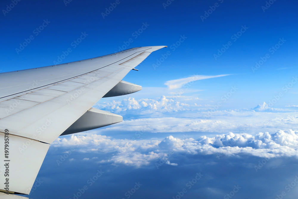 Aerial view of plane window above clouds under blue sky. View from aircraft window Aerial view of plane window above clouds under blue sky. View from aircraft window