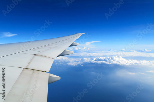 Aerial view of plane window above clouds under blue sky. View from aircraft window
