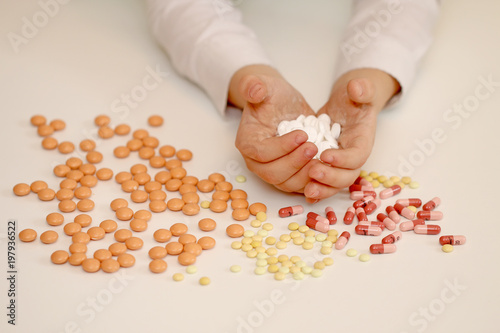 Medication on a white background and in the hand, a pin and a pill