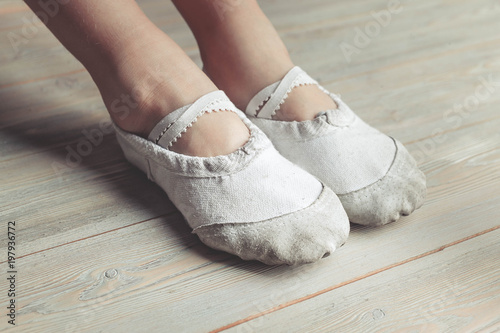 A little dancer. Legs of a girl in ballet slippers on a wooden floor